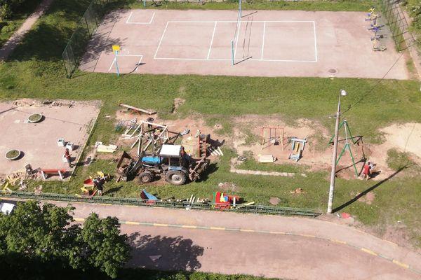 Рабочие монтируют конструкции новой детской площадки и вывозят обломки старой